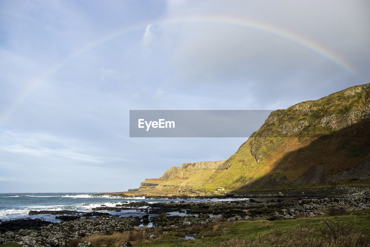 Scenic view of sea against rainbow in sky