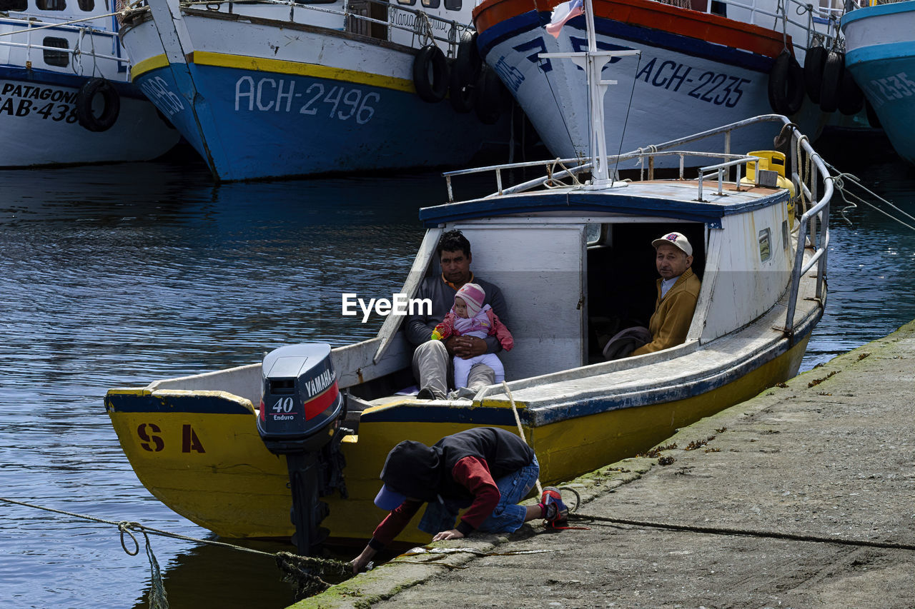 PEOPLE SITTING ON BOATS MOORED IN SEA