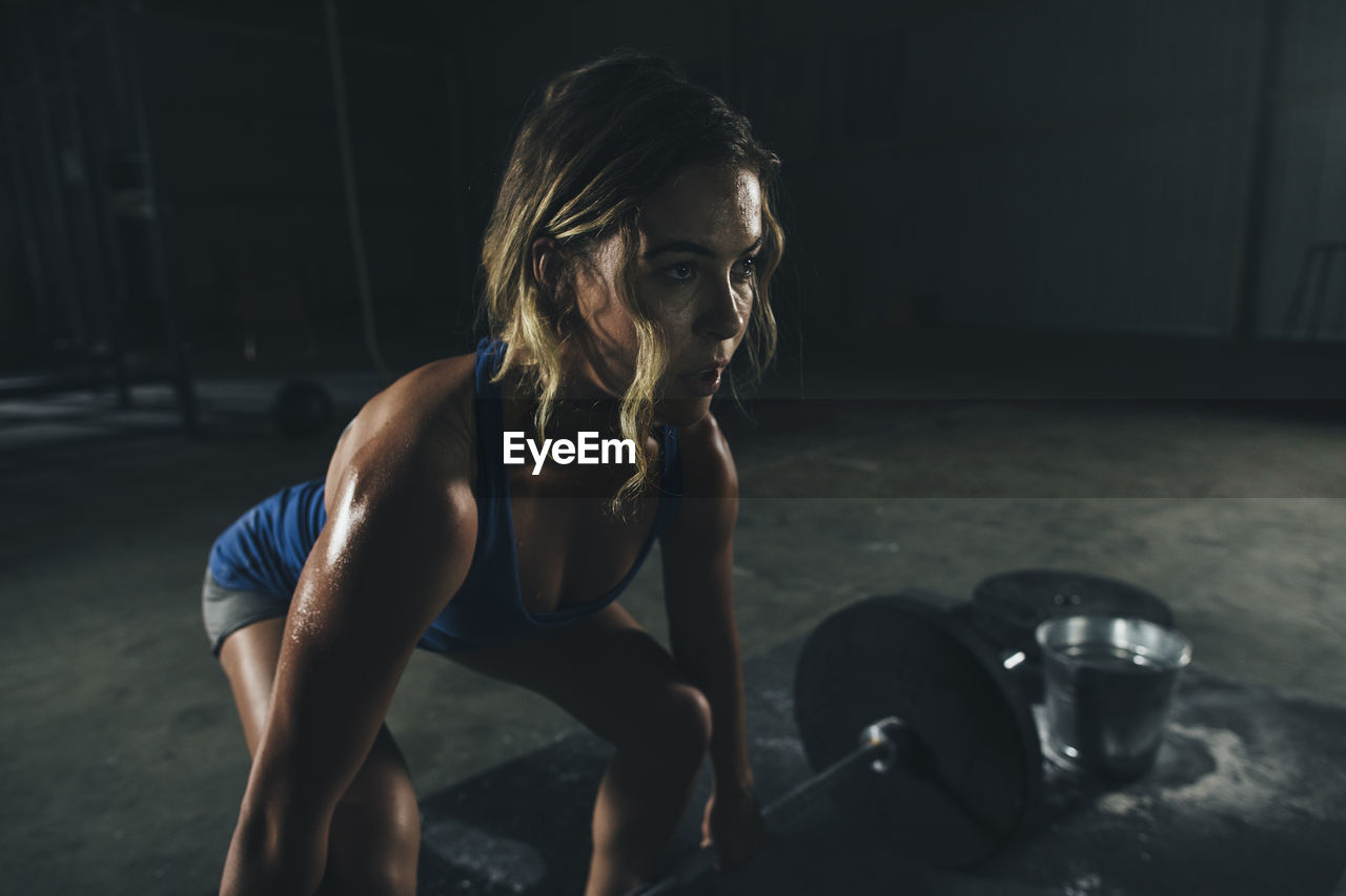 Confident female athlete lifting barbell in gym