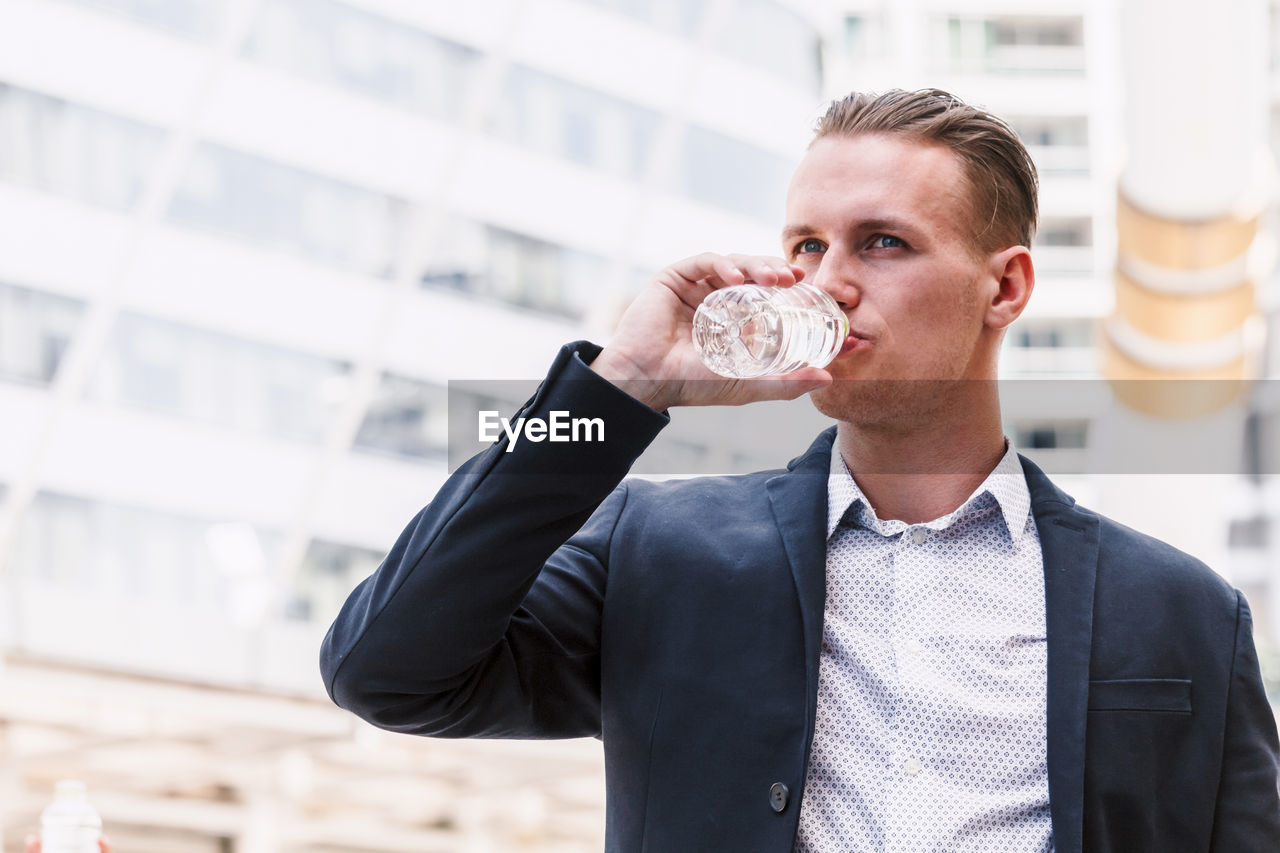 Businessman drinking water while standing outdoors