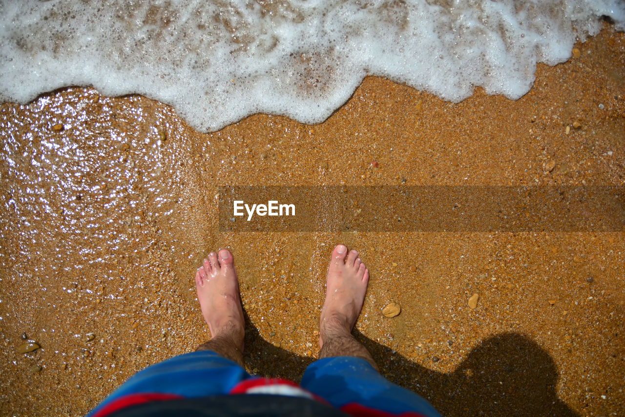 LOW SECTION OF PERSON LEGS ON SHORE