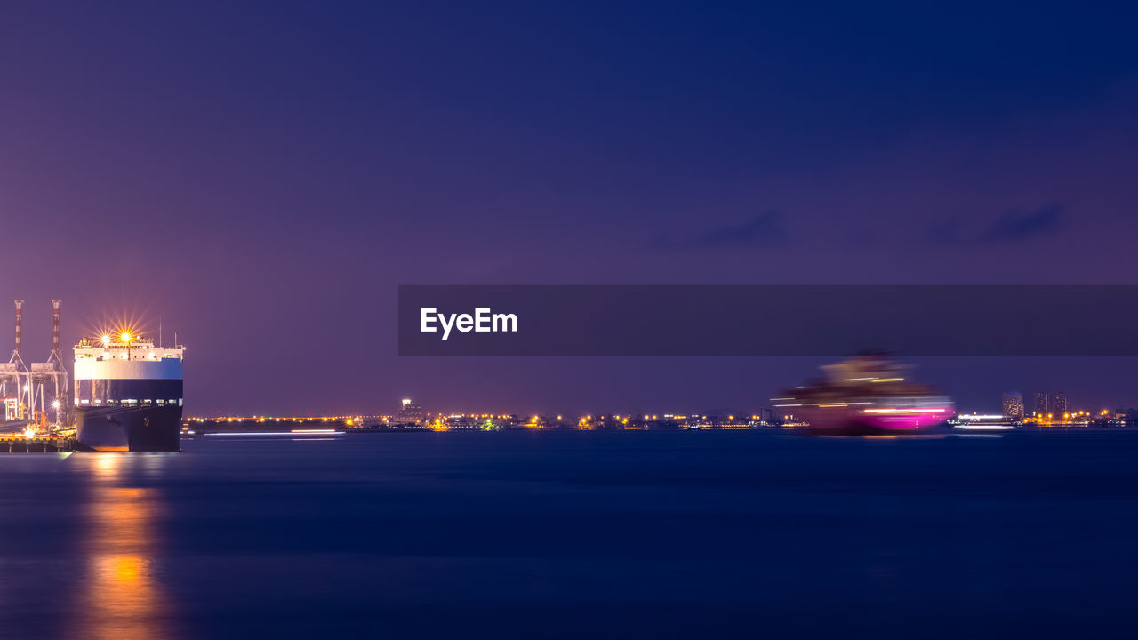 Long exposure at night scene shot shipping port and motion blur shipping sailing on the sea