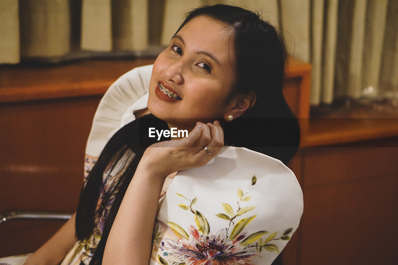 Portrait of smiling young woman sitting at home