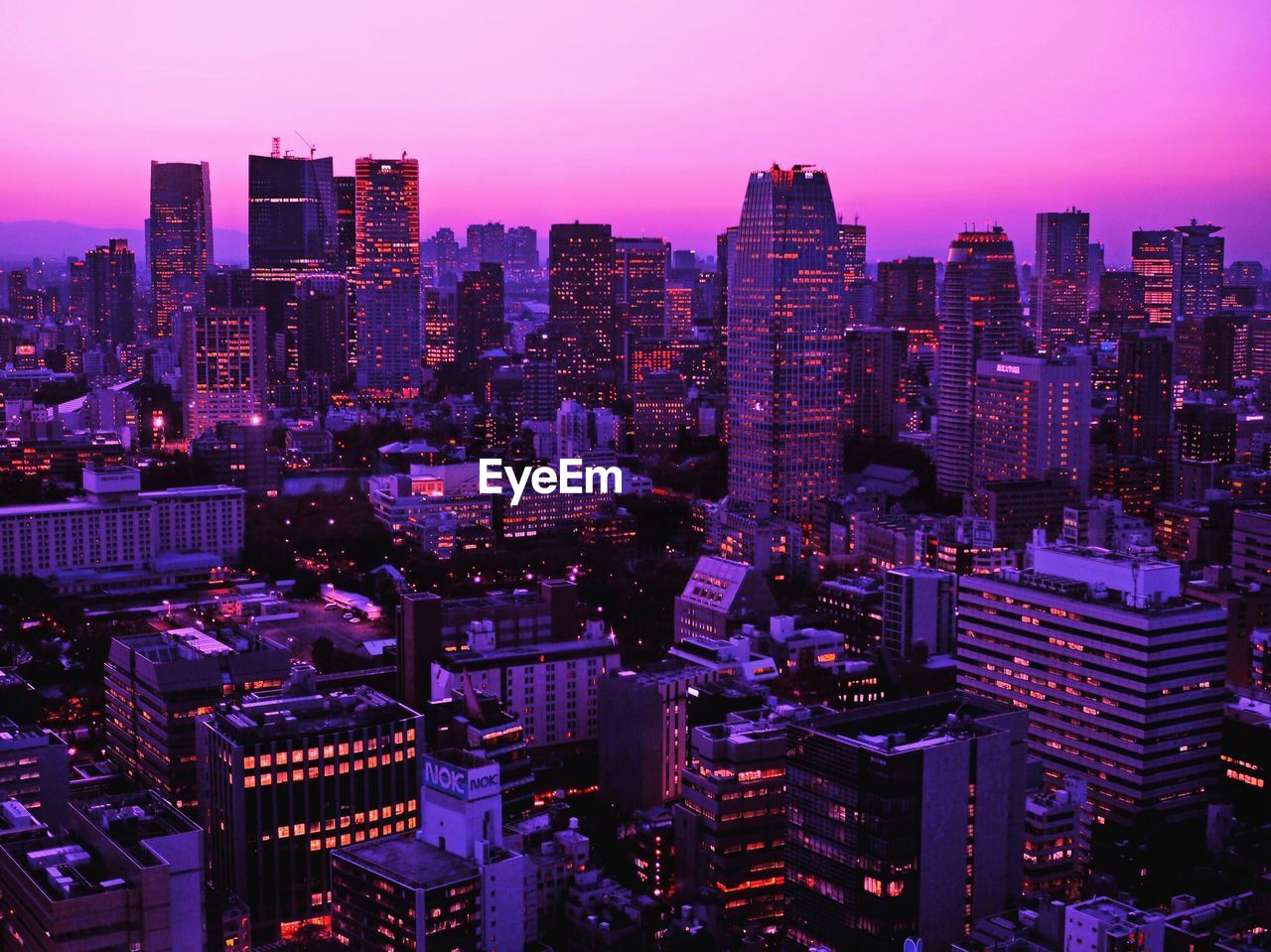 Illuminated buildings against purple sky in city at dusk