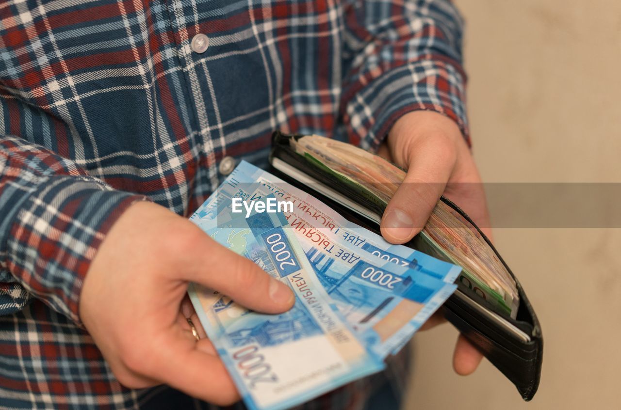 Midsection of man removing paper currencies from wallet