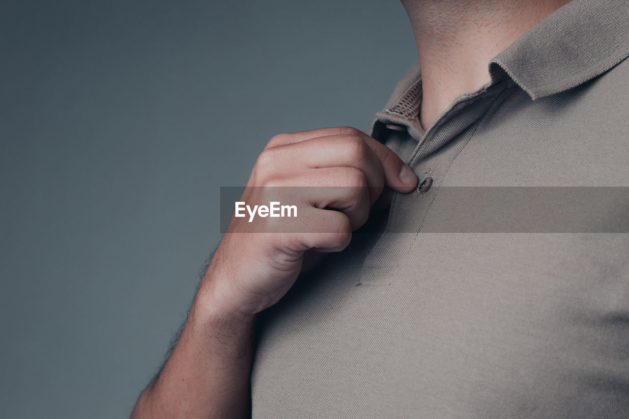 Close-up of man wearing polo shirt over gray background