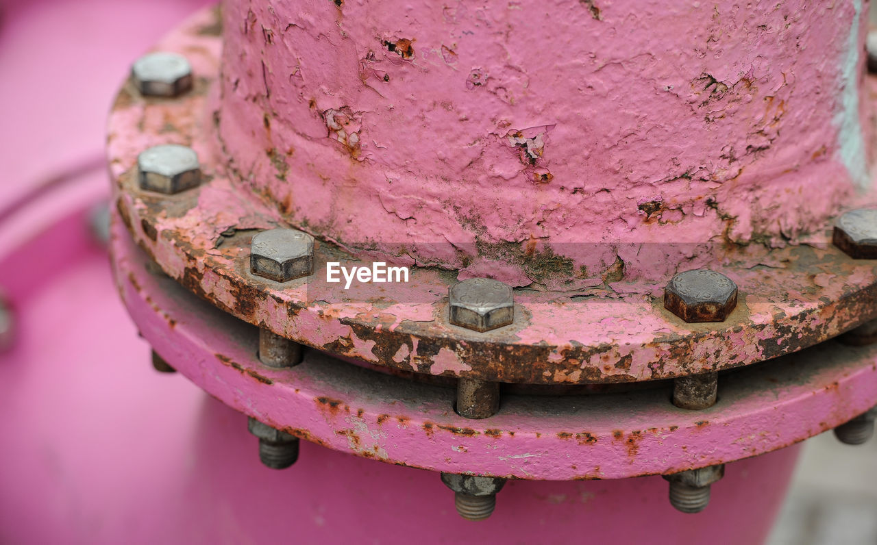 CLOSE-UP OF RUSTY METAL ON PINK METALLIC CONTAINER