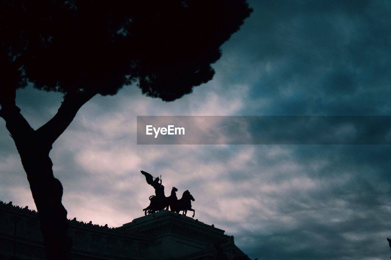 SILHOUETTE OF STATUE AGAINST CLOUDY SKY