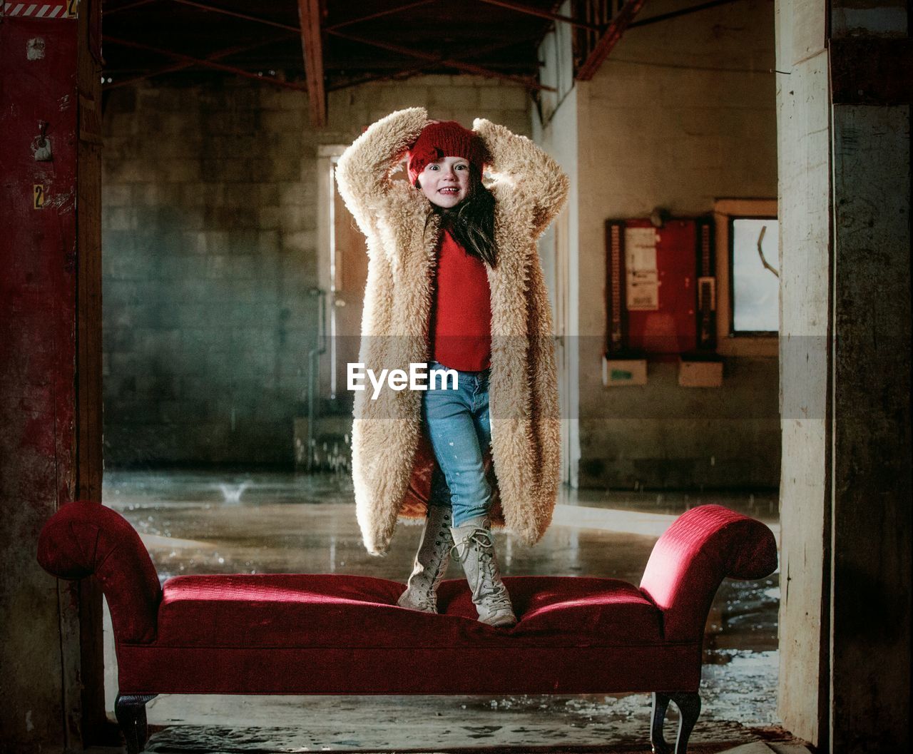 Full length of girl standing on sofa indoors