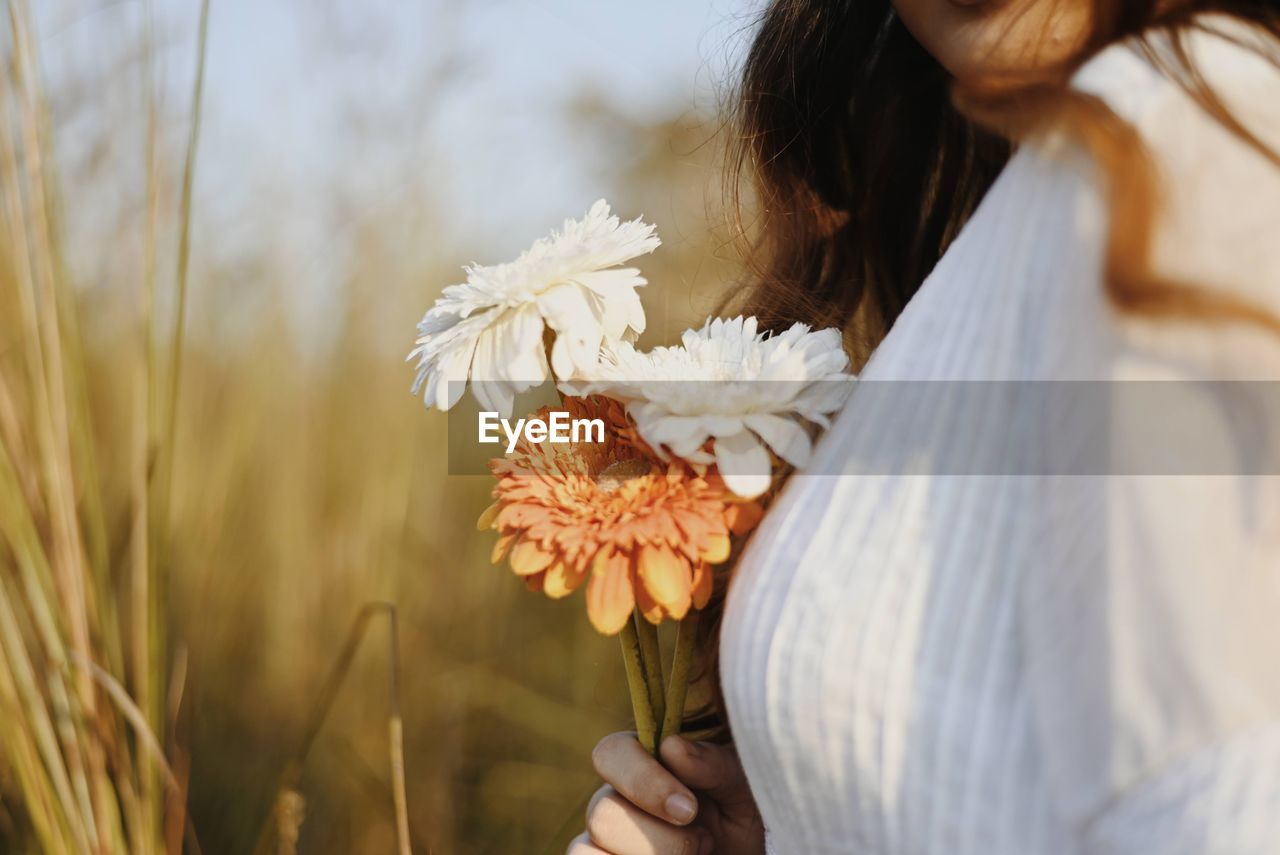 Close-up of woman holding white flowering plants