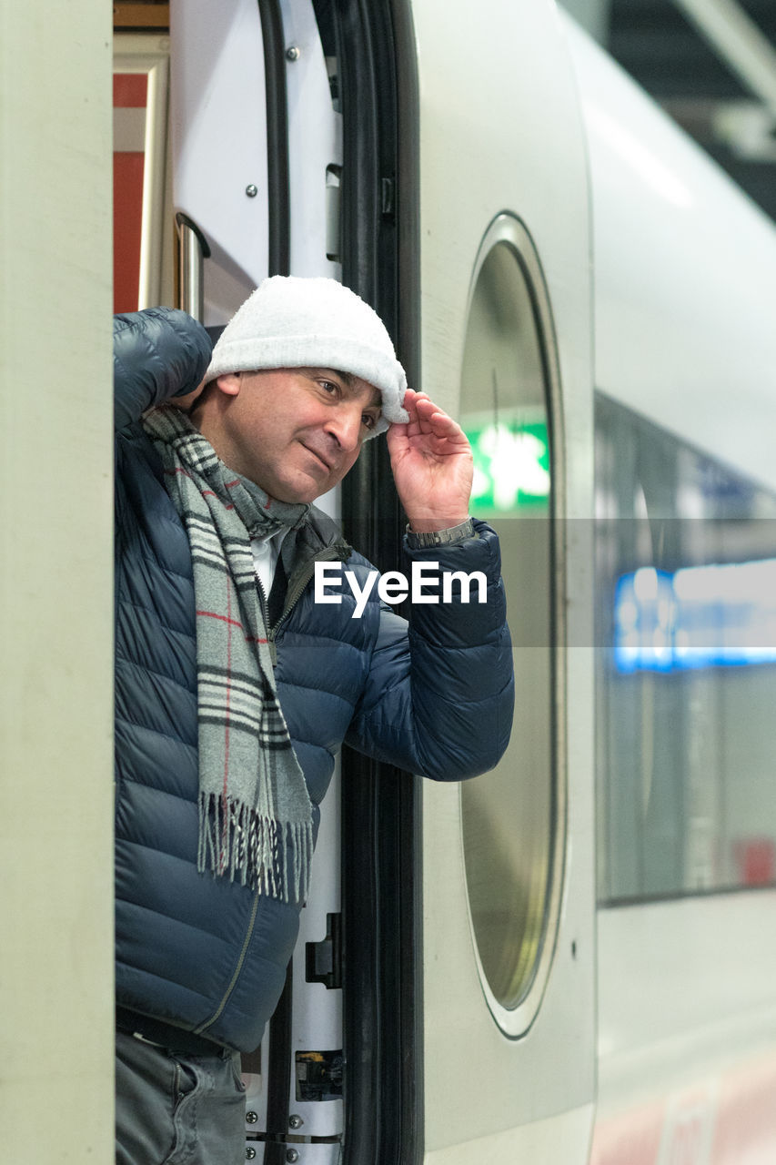 Man wearing knit hat while standing at train entrance