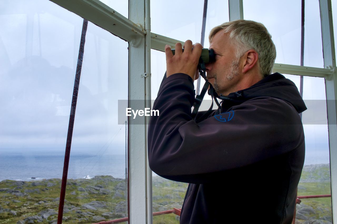 FULL LENGTH OF MAN HOLDING CAMERA AGAINST SKY