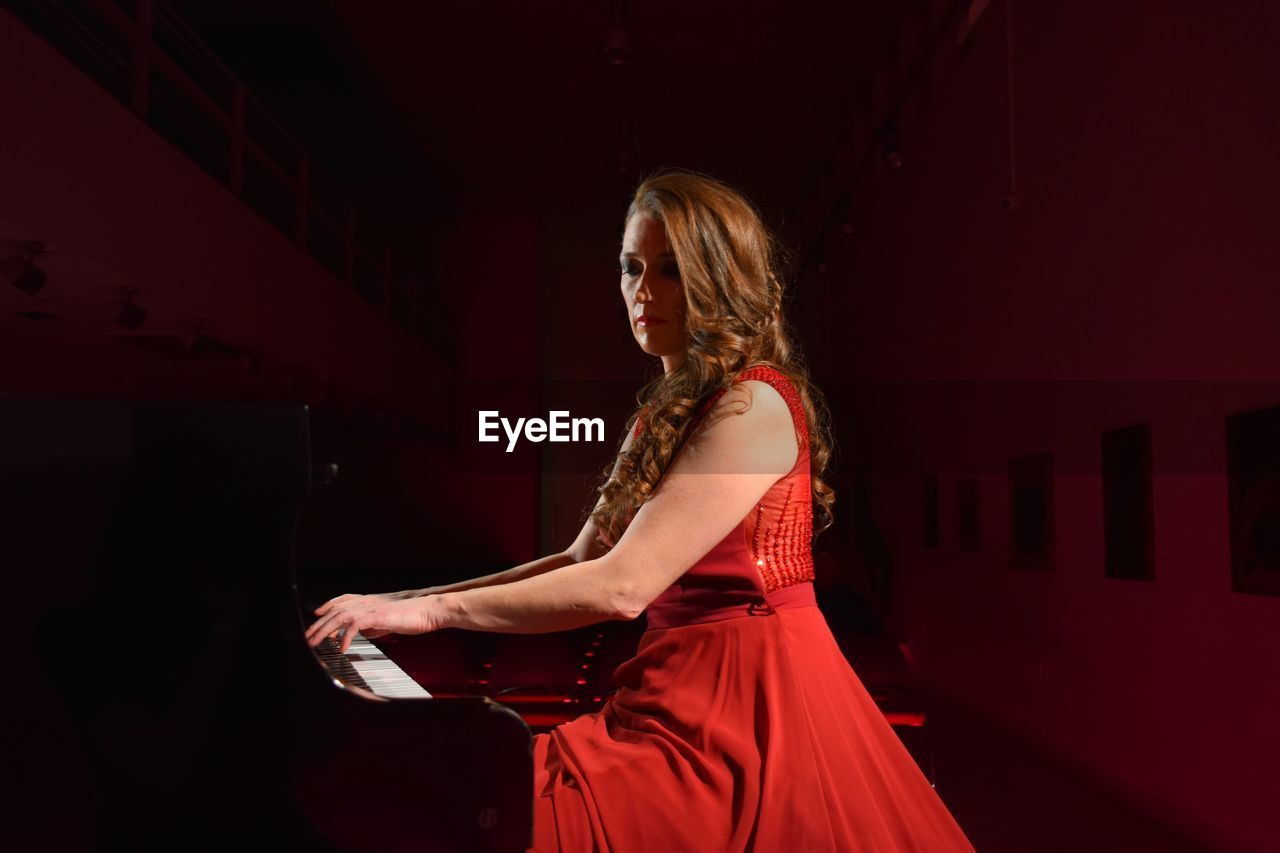 Beautiful musician playing piano on stage in theater