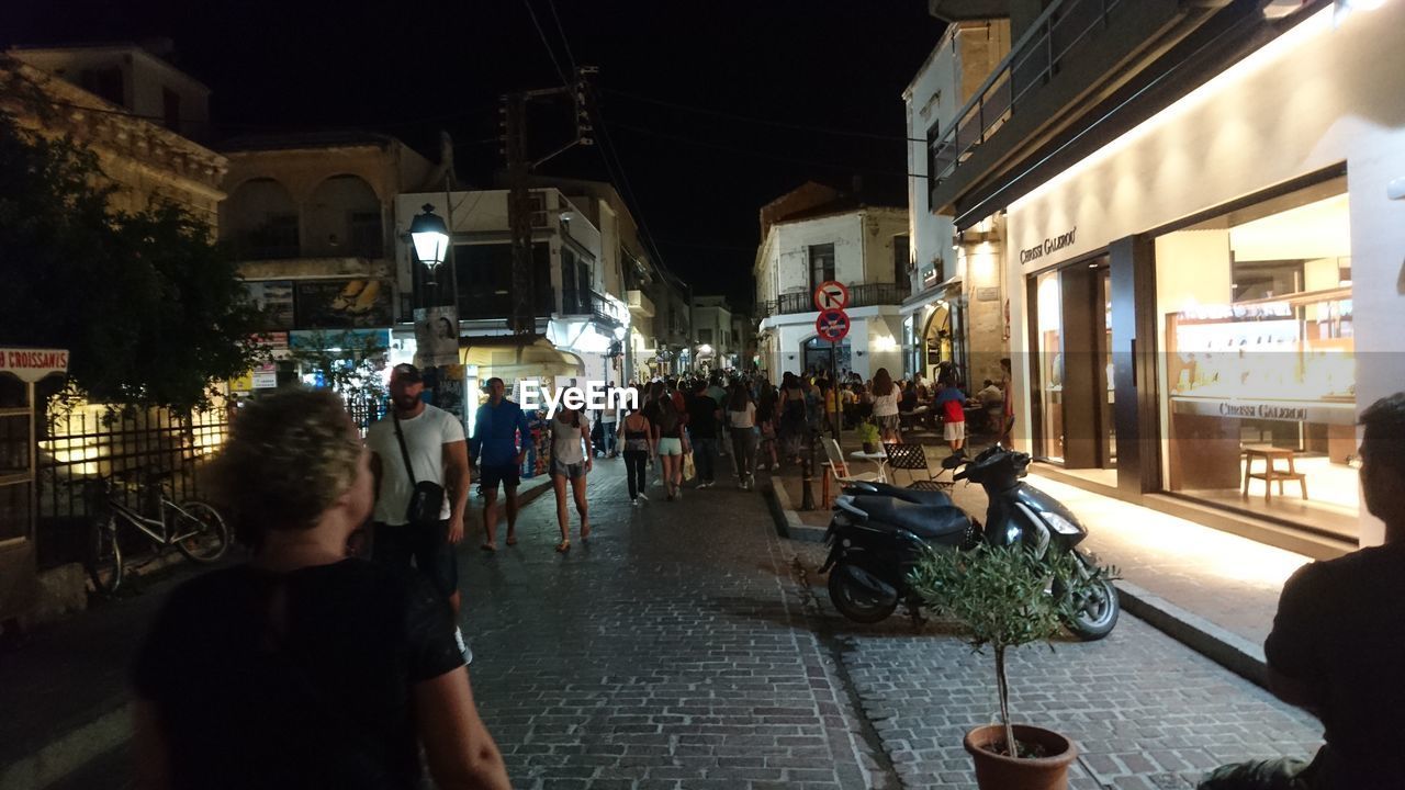 PEOPLE ON ILLUMINATED STREET AT NIGHT