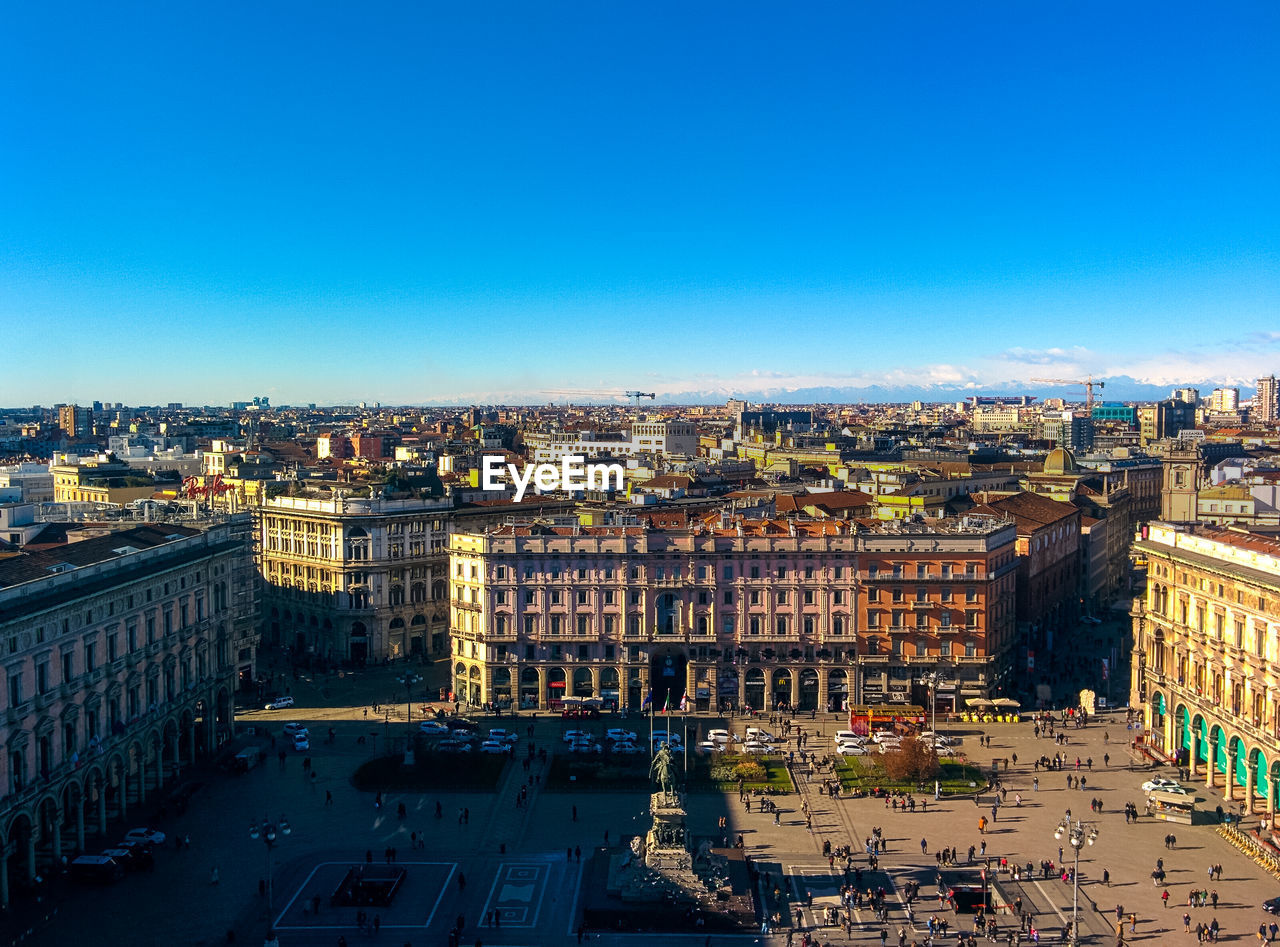 HIGH ANGLE VIEW OF BUILDINGS IN CITY AGAINST BLUE SKY