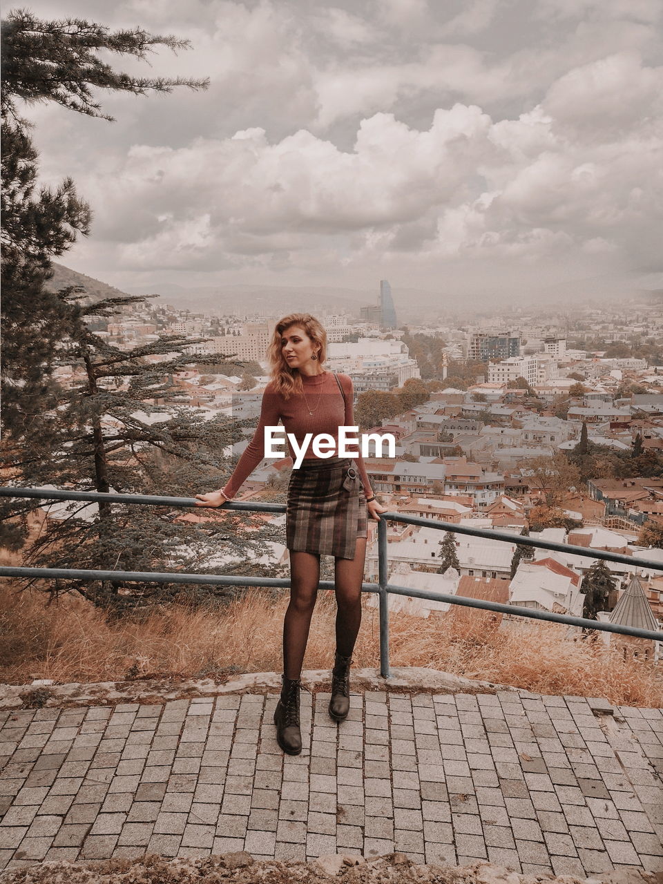 Full length of young woman standing against sky in city