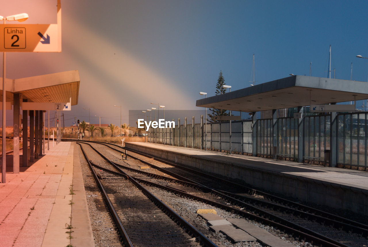 Railway tracks at railroad station in city against sky