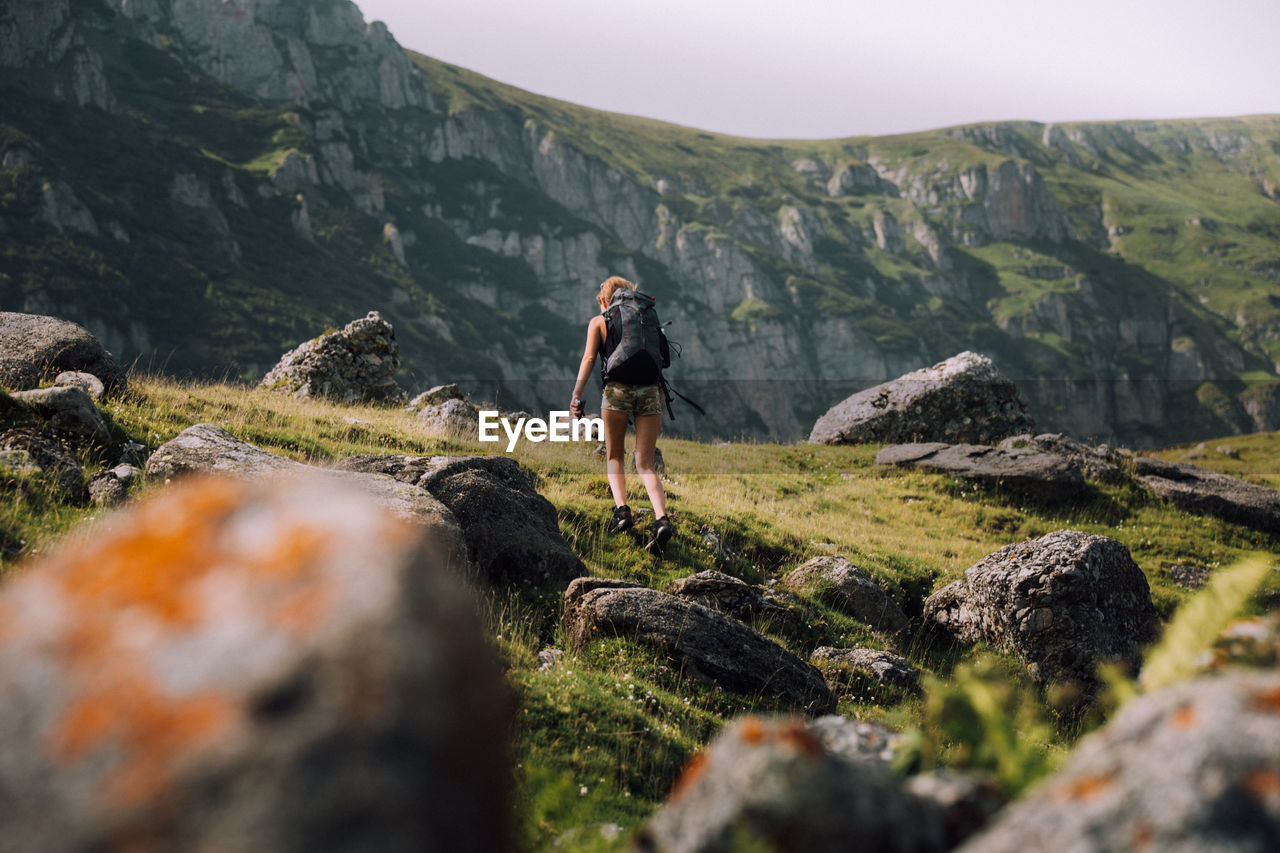 Low angle view of female hiker with backpack walking on mountain