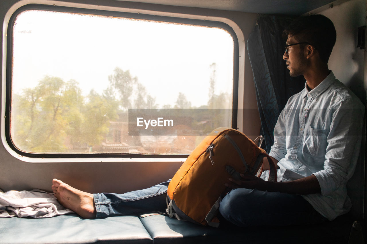 Sitting in a train, looking through the window. 