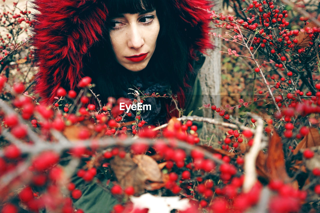 Woman wearing fur coat amidst red berries