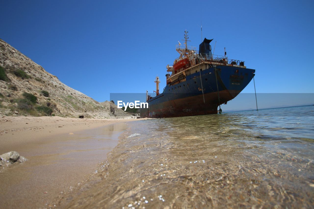 ABANDONED BOAT IN SEA AGAINST CLEAR SKY