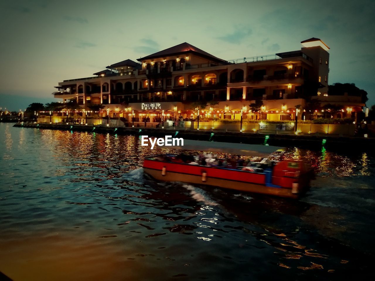 BOAT SAILING ON SEA BY ILLUMINATED BUILDINGS AGAINST SKY AT NIGHT