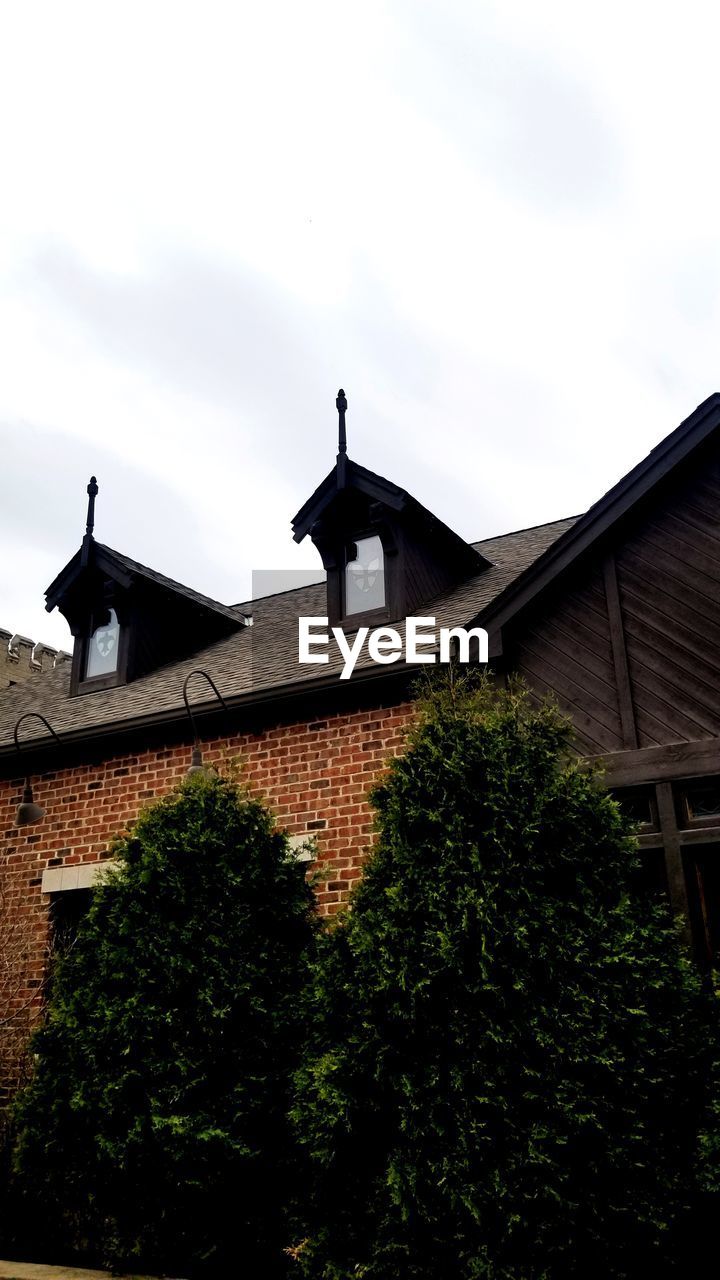 LOW ANGLE VIEW OF BUILDING BY TREES AGAINST SKY