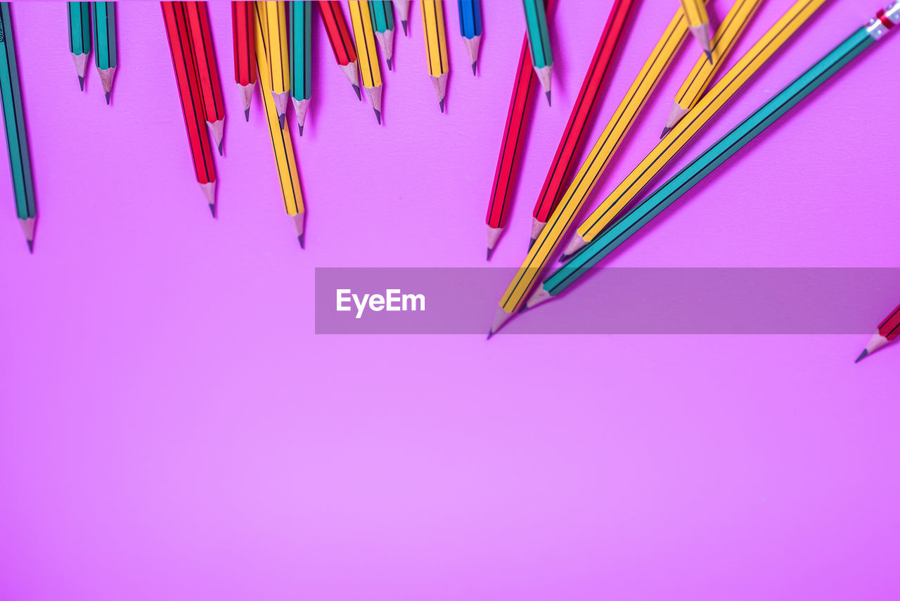 High angle view of multi colored pencils against purple background