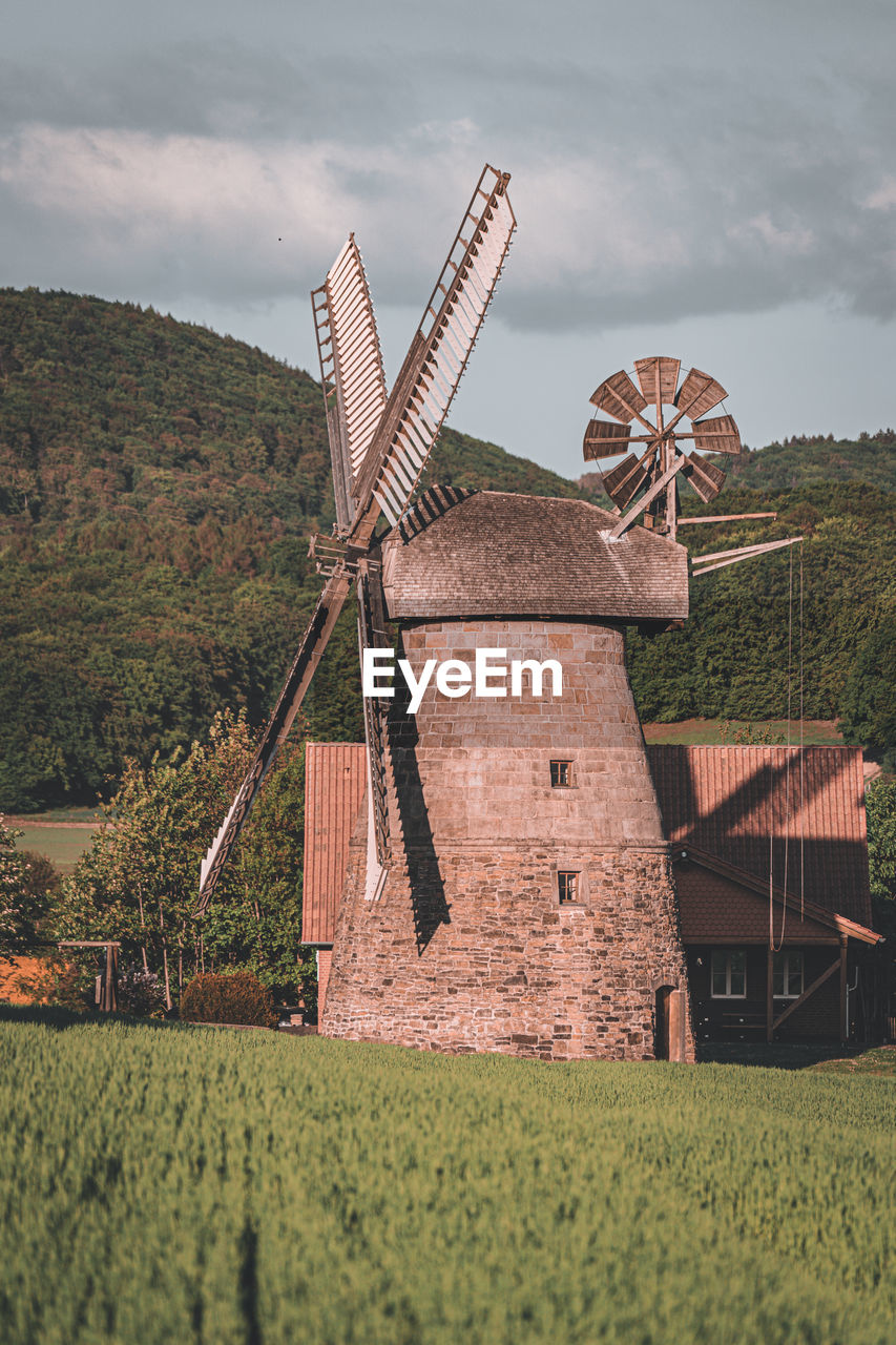 Traditional windmill on field against sky