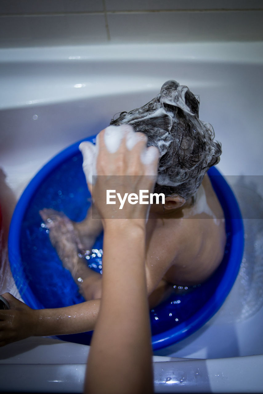 Close-up of hand cleaning baby in bath tub