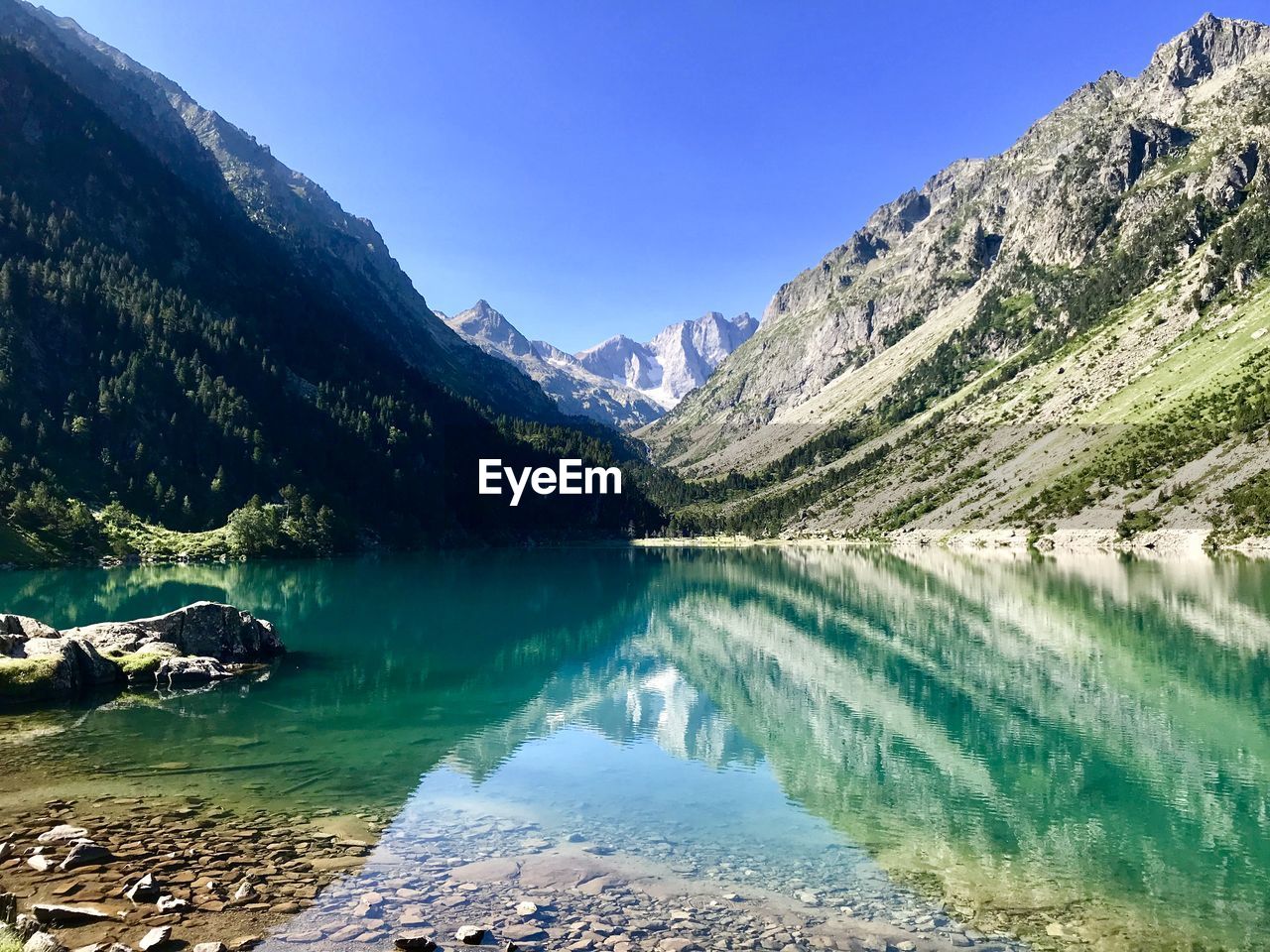 Scenic view of lake and mountains against blue sky