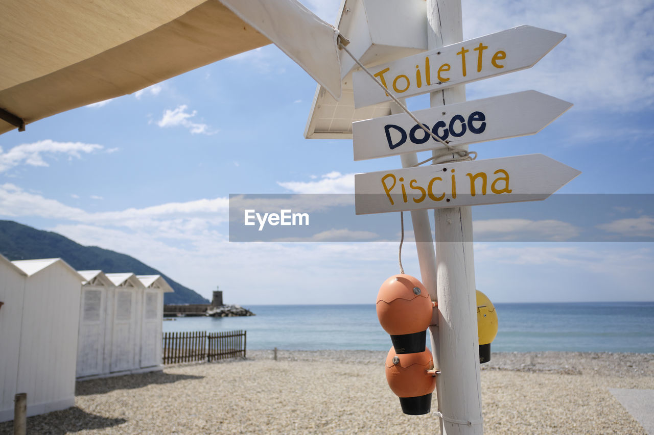 INFORMATION SIGN ON BEACH AGAINST SEA