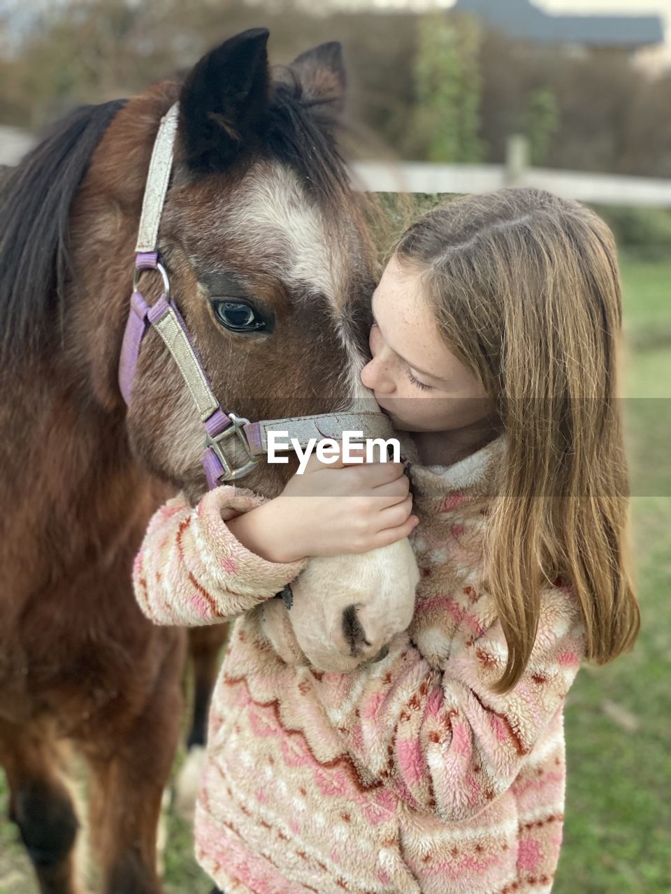 Girl giving kisses to her pony.