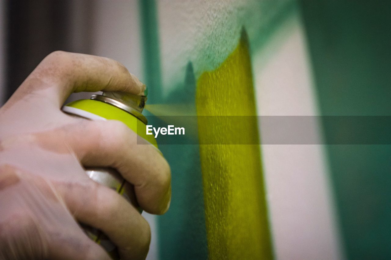 Close-up of hand painting wall with spray paint