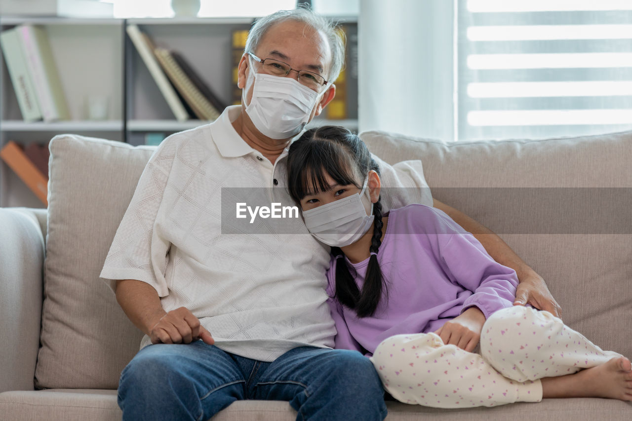 Portrait of grandfather and daughter sitting on sofa