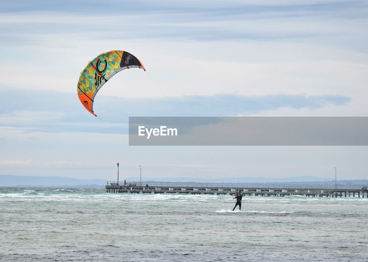 Person kitesurfing sea against sky