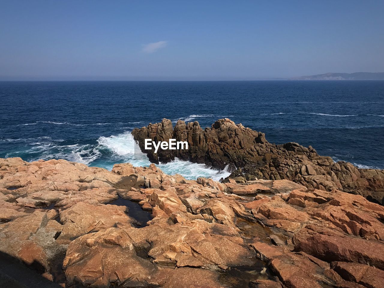 Rock formations on shore against blue sky