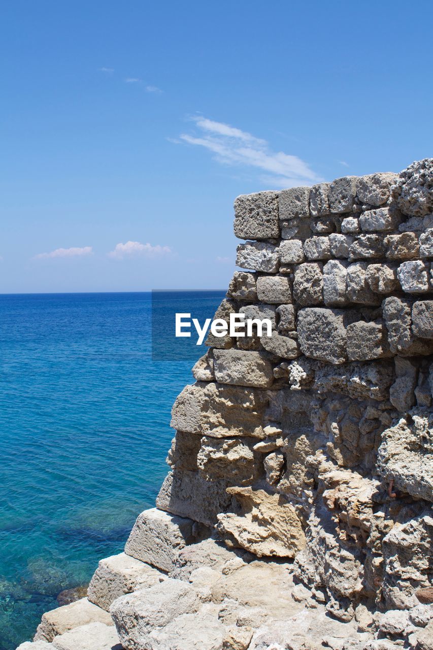 SCENIC VIEW OF ROCKS BY SEA AGAINST BLUE SKY