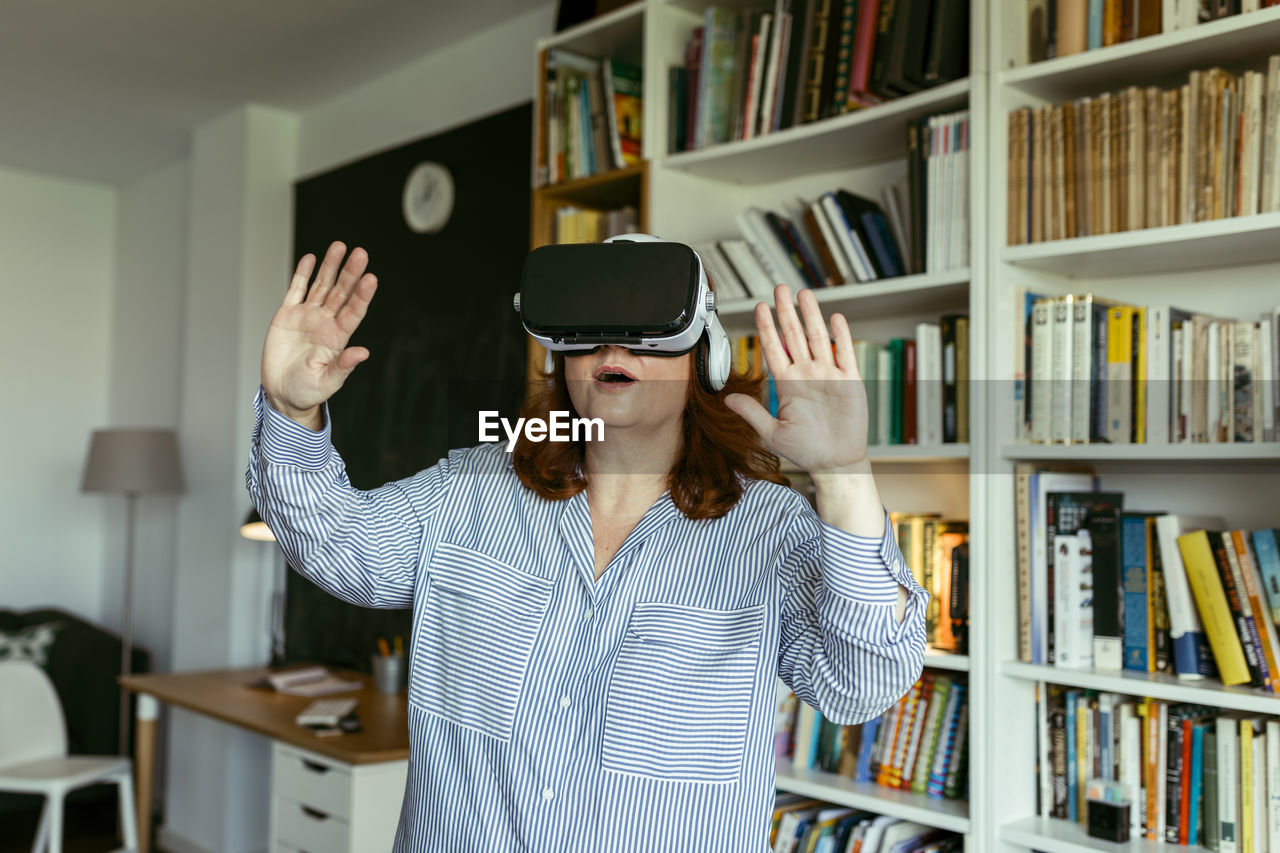 Woman using virtual reality glasses while standing at home