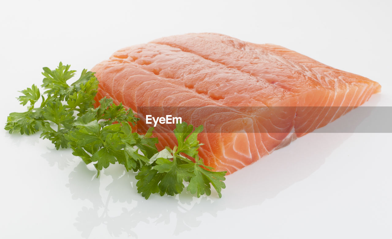 Close-up of raw seafood with herb over white background