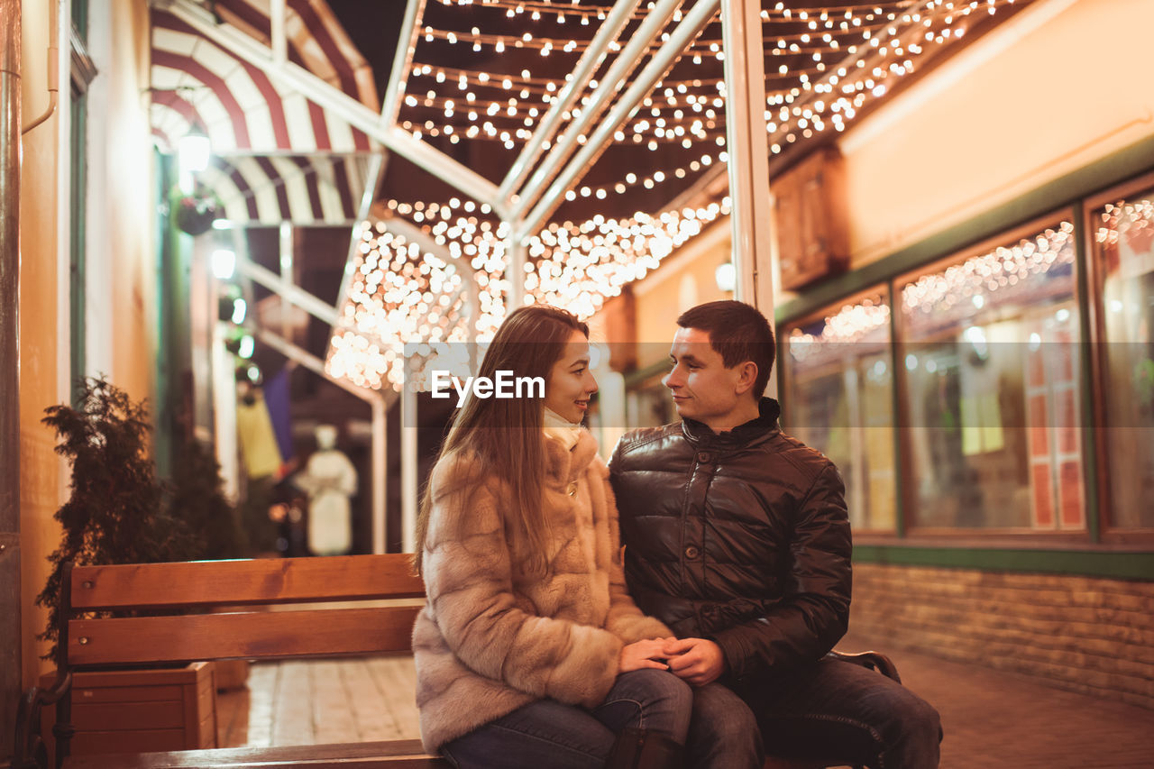 Young couple sitting in illuminated room