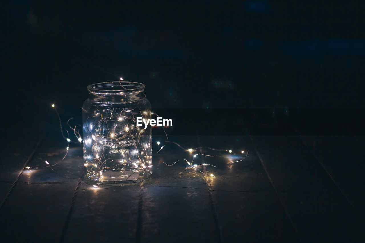 Close-up of illuminated glass jar on table