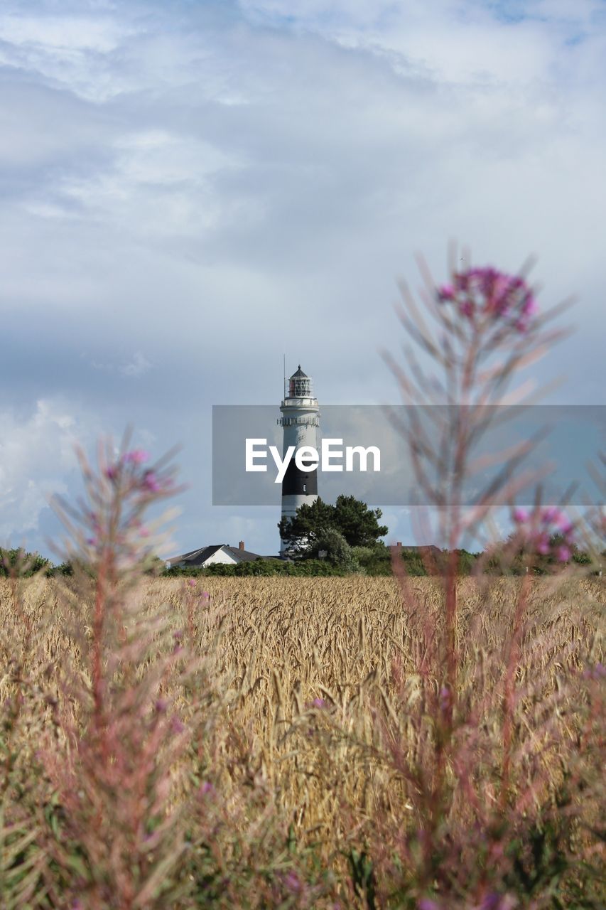 Lighthouse by agricultural field against sky