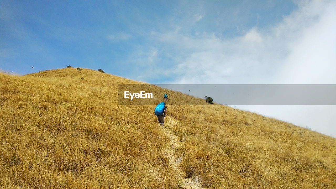 Low angle view of people hiking on mountain against sky