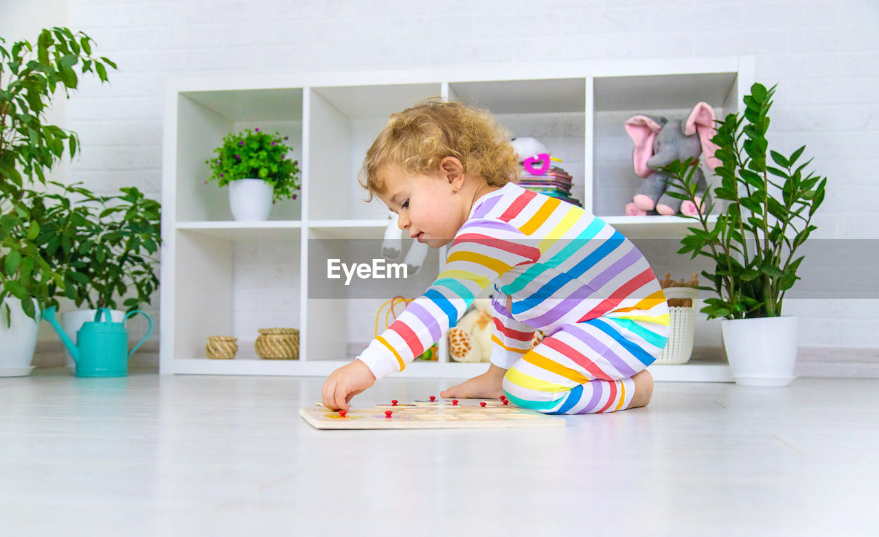 portrait of boy playing with toy on hardwood floor