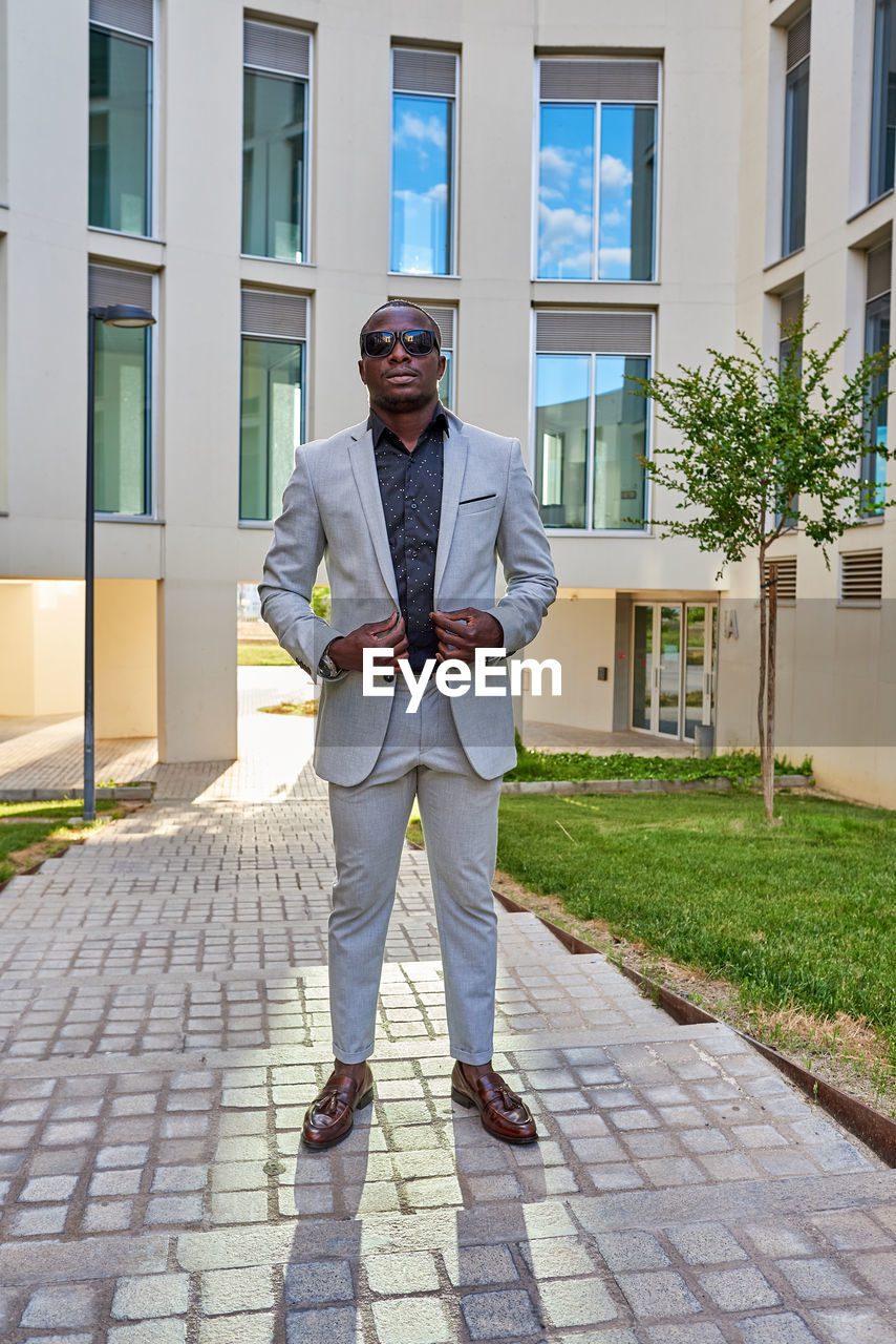 Africanamerican businessman between buildings, with the sun on his back person