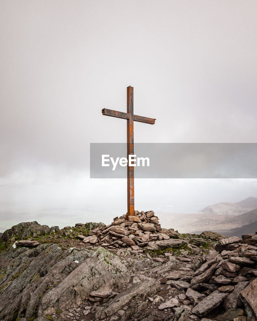 CROSS ON ROCK BY TEMPLE AGAINST SKY