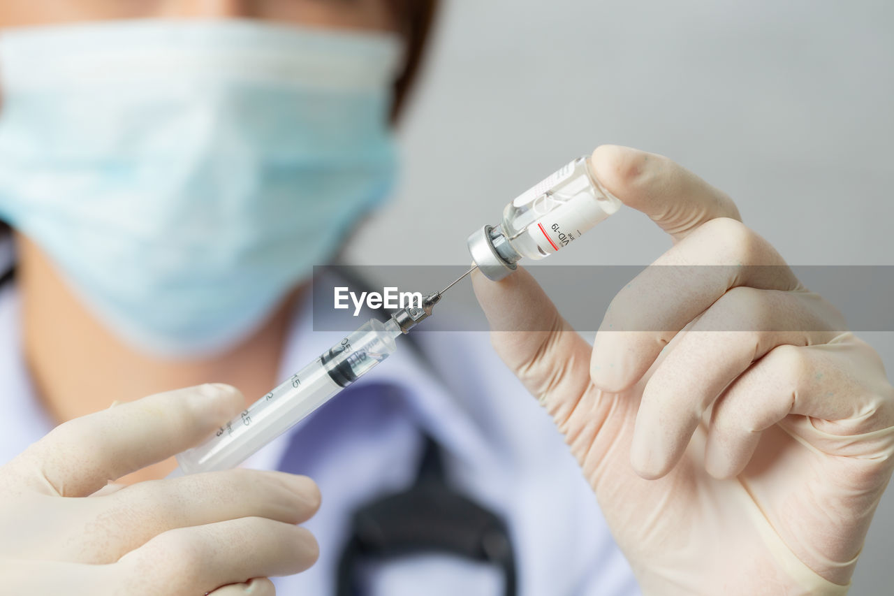 cropped hand of doctor holding syringe