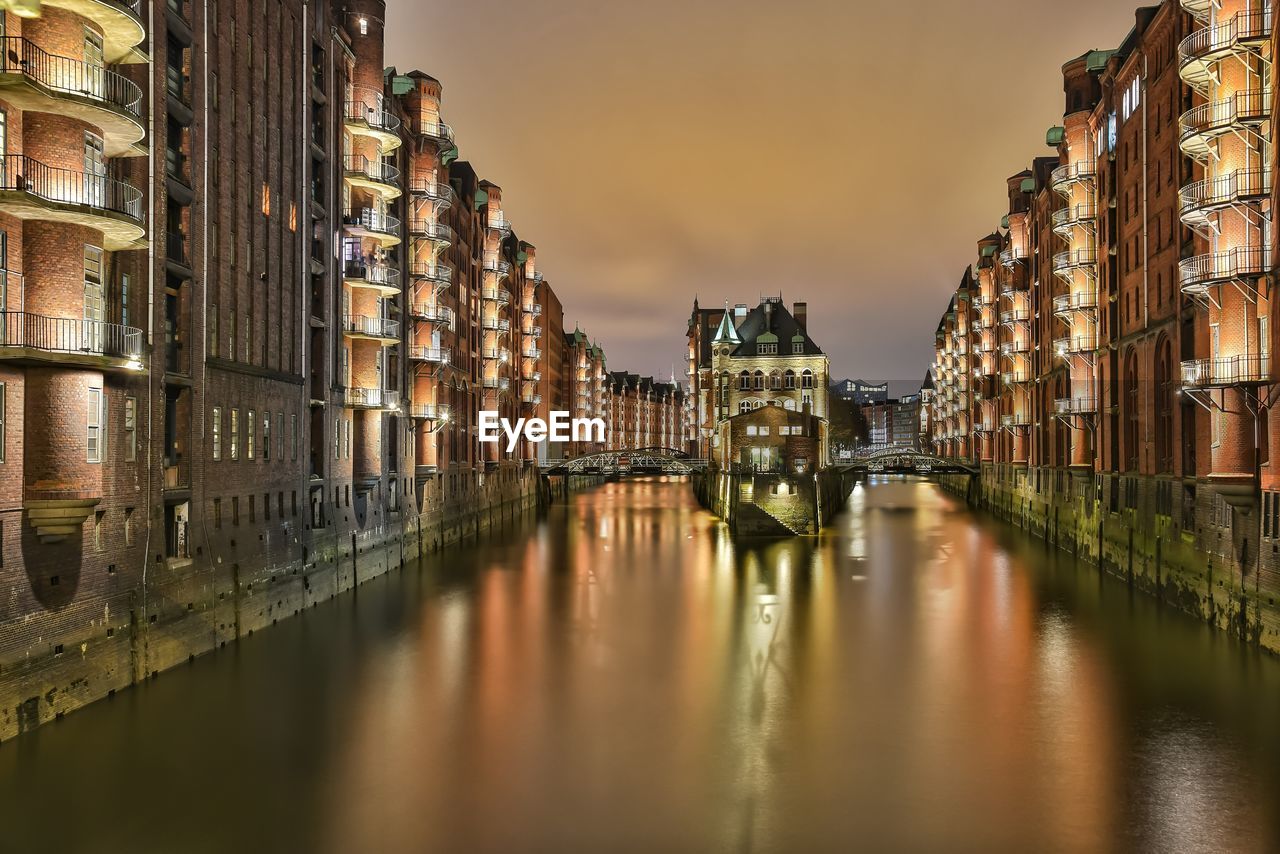 Illuminated bridge over river in city at night