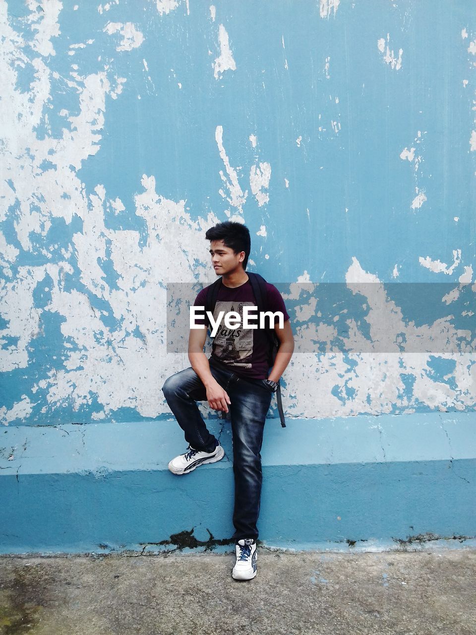 Young man standing against wall